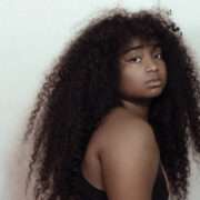 Confident Black woman with long natural curly hair looking over shoulder, expressing bold self-identity and style