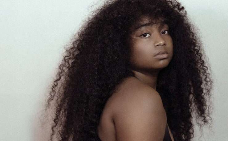 Confident Black woman with long natural curly hair looking over shoulder, expressing bold self-identity and style
