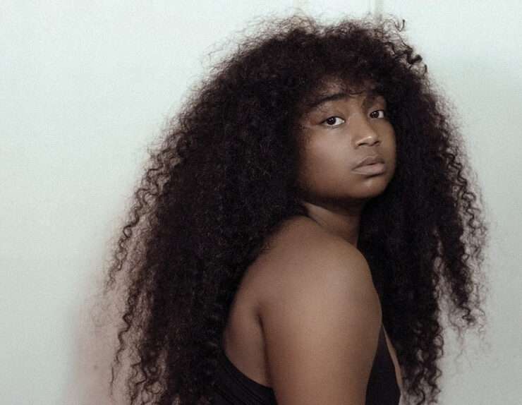 Confident Black woman with long natural curly hair looking over shoulder, expressing bold self-identity and style