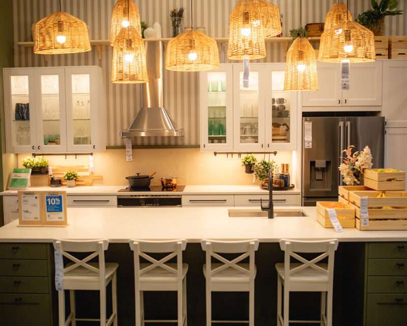IKEA House Warming IKEA Union Square kitchen display featuring rattan pendant lights, white cabinets, and modern Scandinavian design