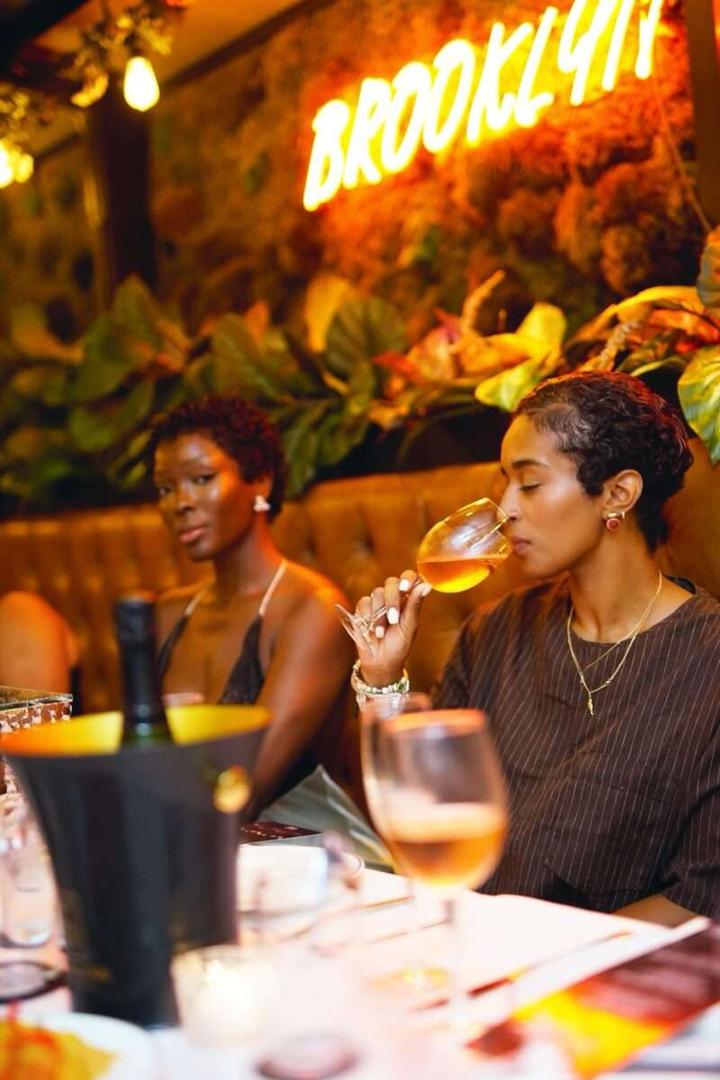 Guest sipping Le Kool Champagne at the Brooklyn Chop House table